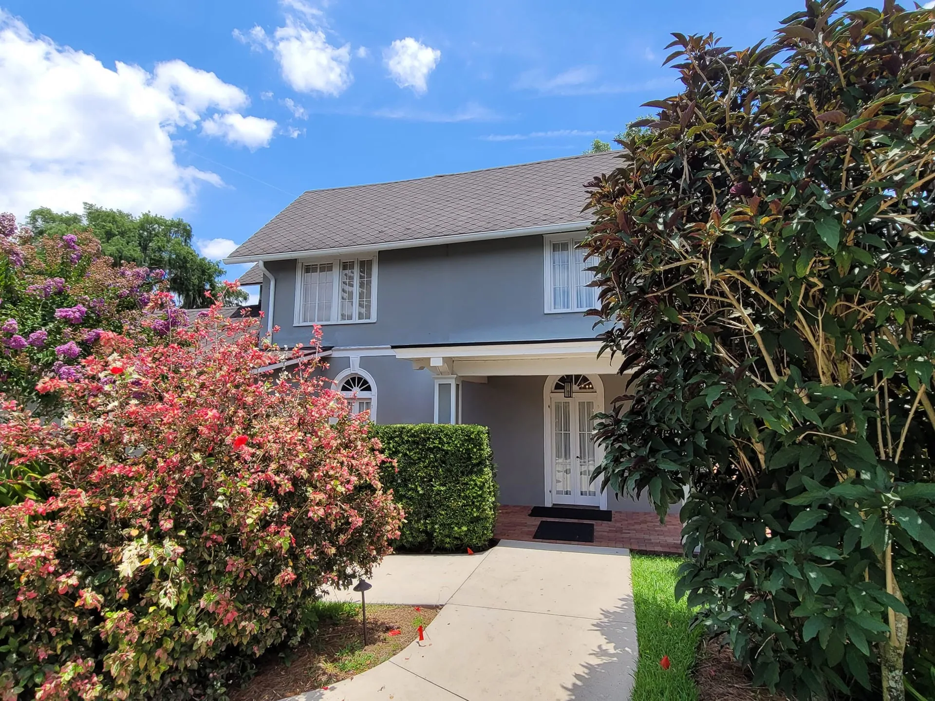 Two story gray stucco home white gutters front walkway shrubs, Sanford